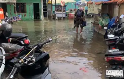 Warga berjalan digenangan banjir rob yang merendam Jalan Dermaga Ujung 1 Muara Angke, Jakarta Utara, pada Jumat (13/12/2024). [Foto: Ist]