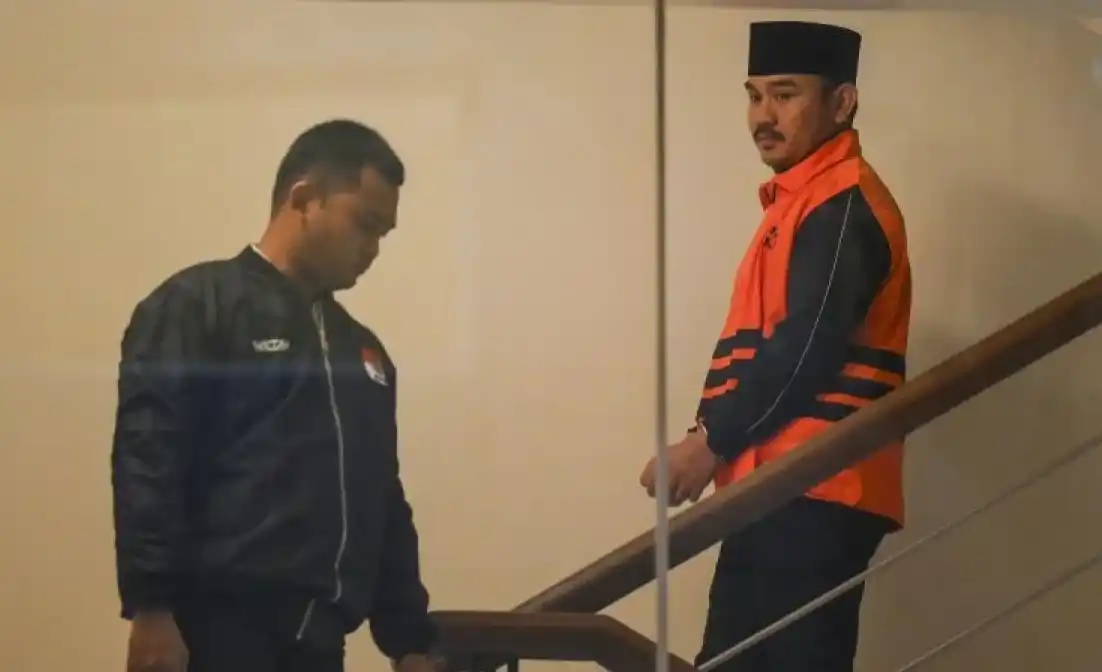 Bupati Bekasi Ade Kuswara Kunang berjalan mengenakan rompi tahanan usai terjaring operasi tangkap tangan (OTT) di Gedung Merah Putih KPK, Jakarta, Sabtu (20/12/2025). KPK menahan Bupati Bekasi Ade Kuswara Kunang, ayah bupati H. M. Kunang dan pihak swasta Sarjan setelah ditetapkan tersangka dugaan tindak pidana korupsi terkait suap ijon proyek di Kabupaten Bekasi.