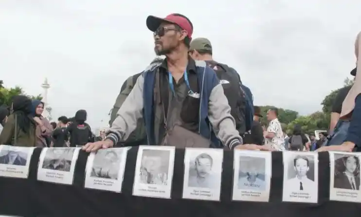 Seorang pengunjuk rasa di Aksi Kamisan bersama foto-foto sejumlah korban pelanggaran HAM berat masa lalu.