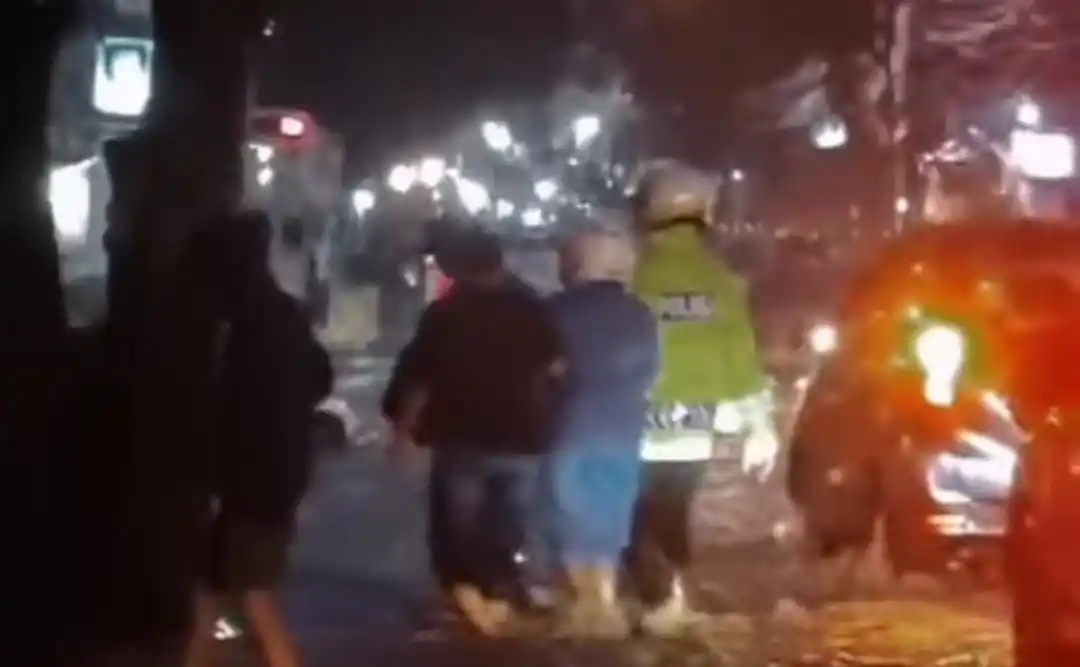 Wakasat Lantas Polresta Bandung, AKP Agus Budi saat membantu seorang Ibu yang sedang sakit di salah satu ruas jalan di Kabupaten Bandung, Jawa Barat yang saat itu sedang banjir. (Foto: tangkapan layar)