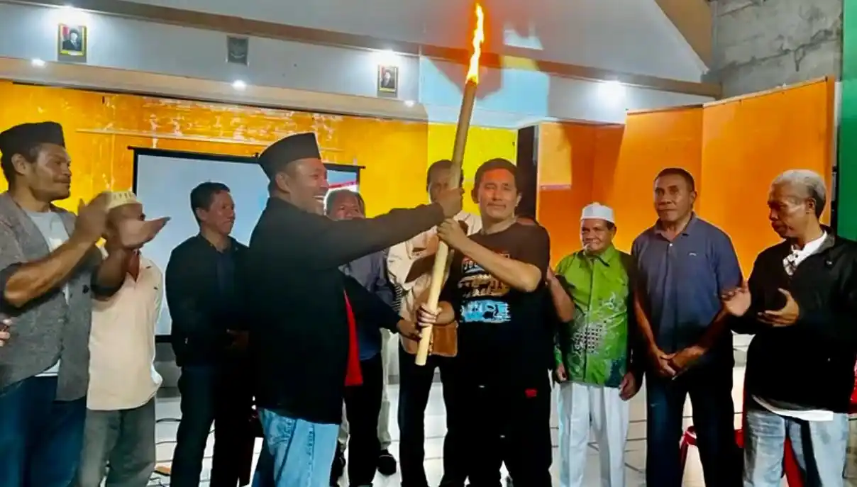 Anggota DPRD Malut, Irfan Soekonae menyerahkan obor perjuangan kepada Koordinator Markas, Muhammad Imam, dalam acara Rembuk Akbar Sesepuh dan Tokoh Bacarita Kota Sofifi yang digelar di Gedung Serbaguna Desa Balbar, Rabu malam (25/6/2025). (Foto: Istimewa)
