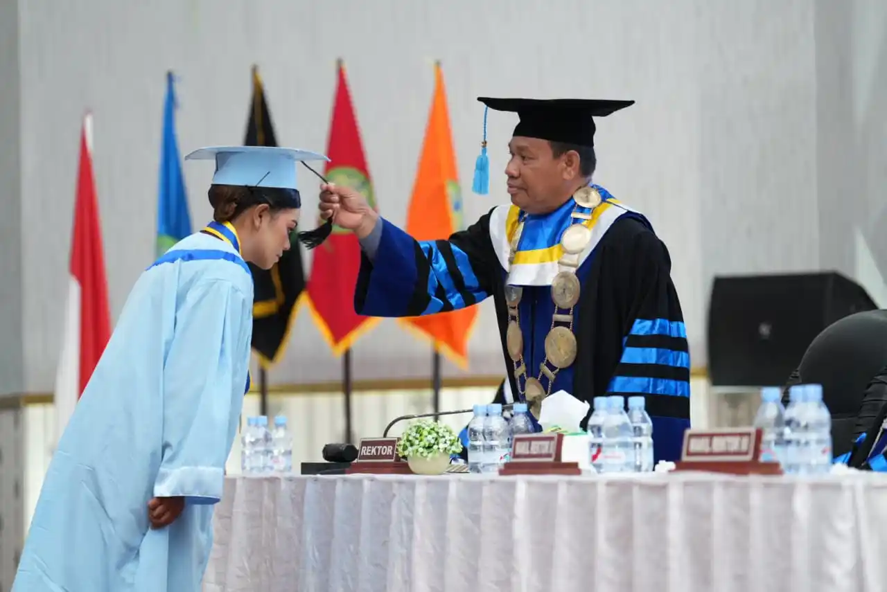 Rektor Unibrah Tidore, Sarbaini A. Karim, memegang topi wisuda salah satu lulusan saat prosesi pengukuhan pada Wisuda Akademik ke-7 di Aula Nuku, Kantor Gubernur Malut, Sofifi, Selasa 4 November 2025 (Foto: Istimewa)